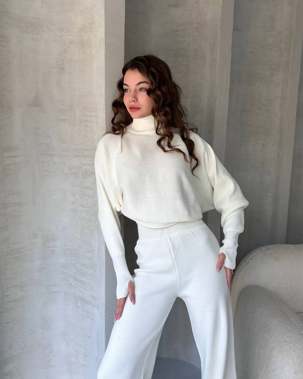 Woman wearing a white outfit against a neutral background