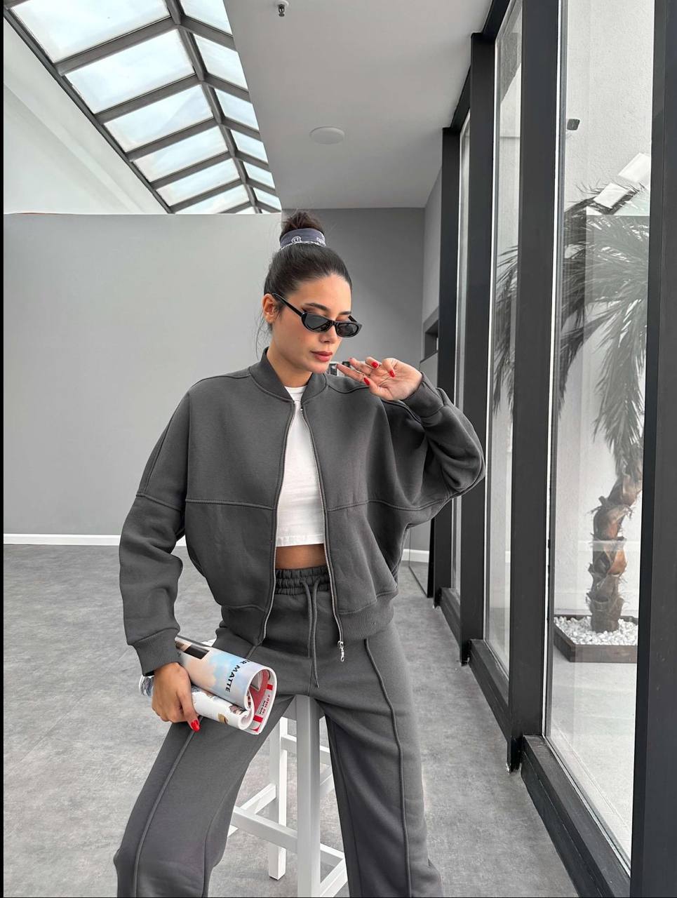 Person wearing a gray outfit with sunglasses indoors