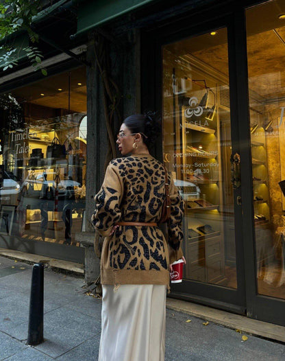 Person wearing a leopard print coat standing outside a store with a glass door.
