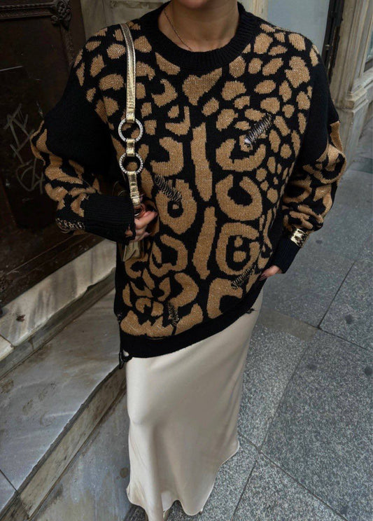 Person wearing a leopard print sweater and holding a handbag on a city street.