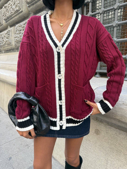 Person wearing a maroon cardigan with white and black trim, holding a black bag.