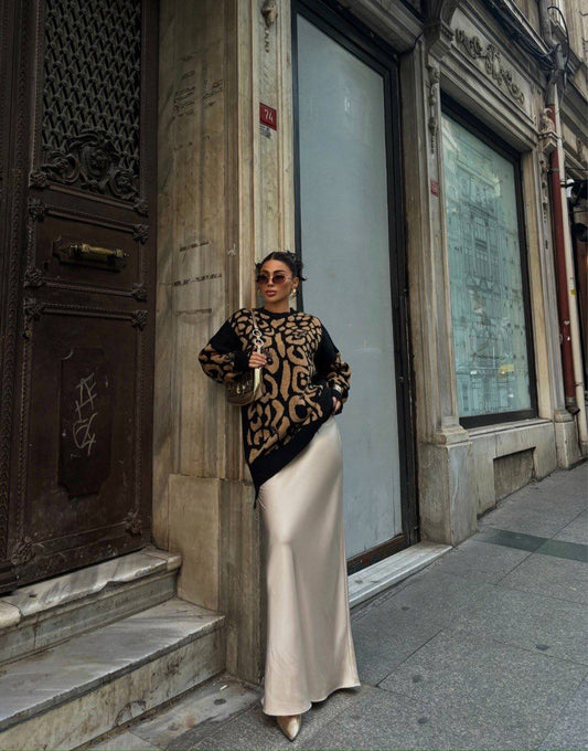Woman in a patterned top and white skirt standing on a city street.
