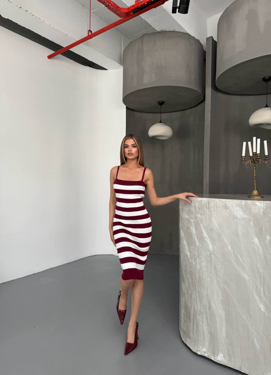 Woman in a red and white striped dress standing in a modern interior setting.