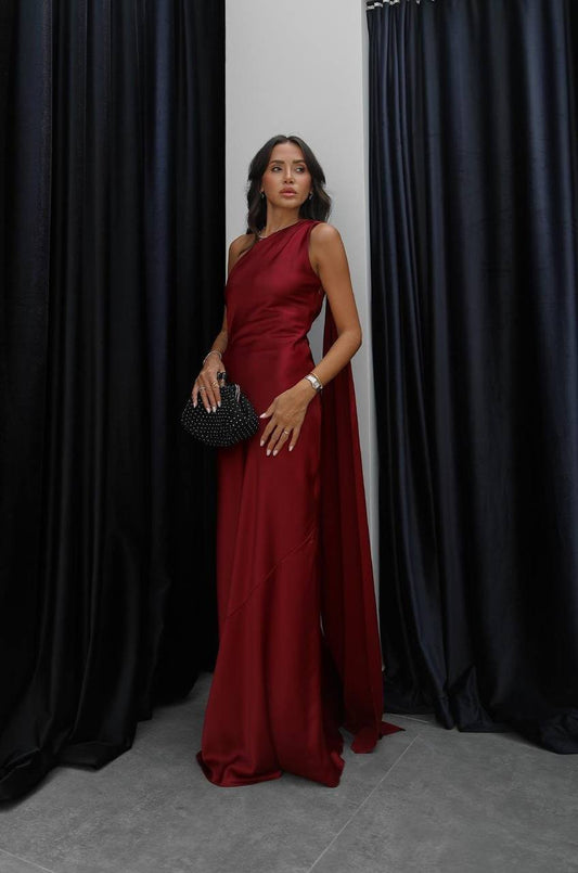 Woman in a red dress standing against black curtains