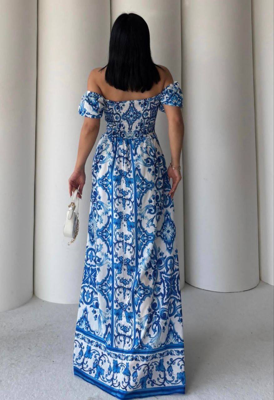 Woman wearing a blue and white patterned dress standing against a neutral background