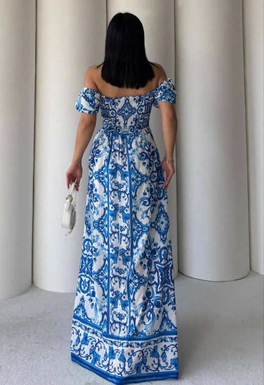 Woman wearing a blue and white patterned dress standing against a neutral background