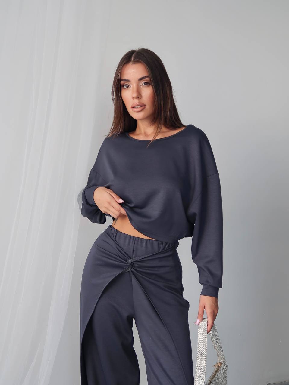 Woman wearing a dark gray outfit against a plain background