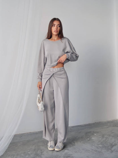 Woman wearing a gray outfit standing against a plain background