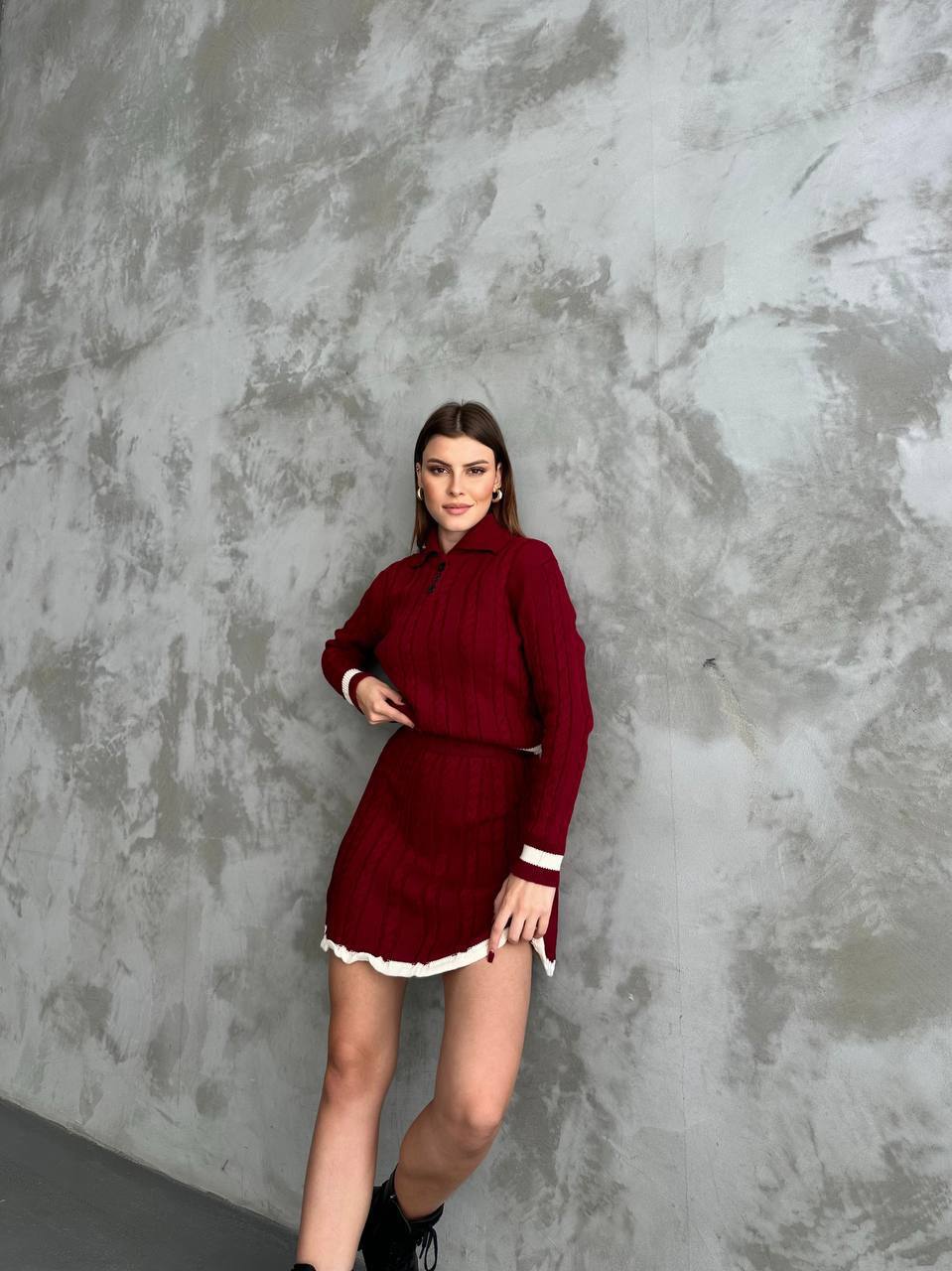 Woman wearing a red outfit against a textured gray wall