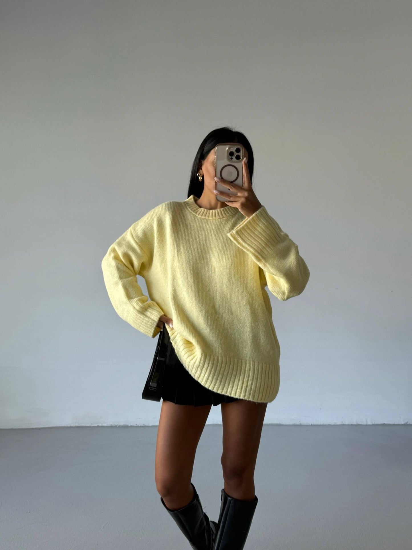 Person wearing a yellow sweater and black skirt against a plain background