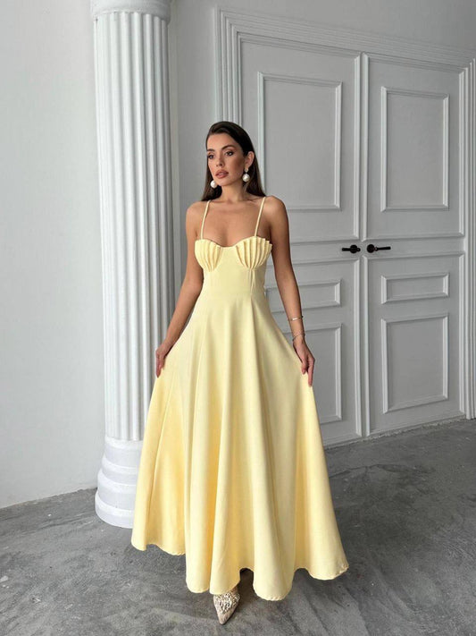 Woman wearing a yellow dress standing in a room with gray walls and a white door.